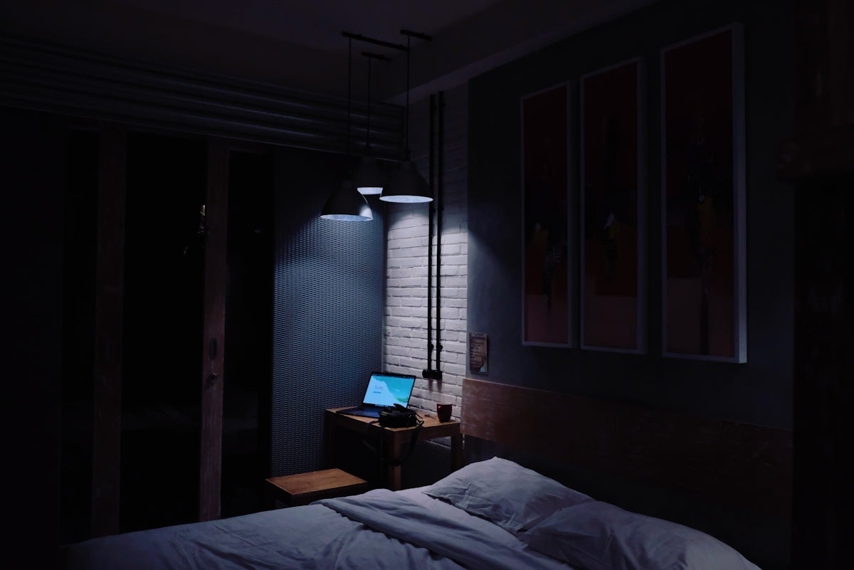 turned-on laptop computer on top of side table inside bedroom